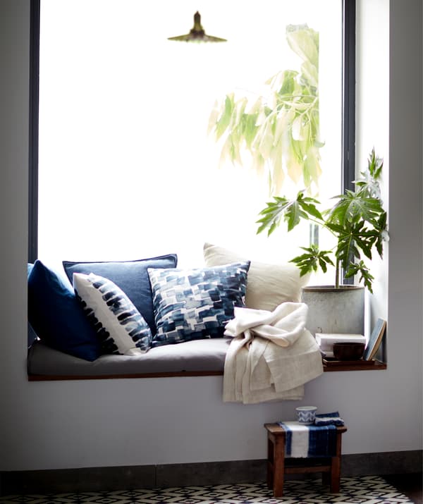 Cushions and a plant in a window seat.