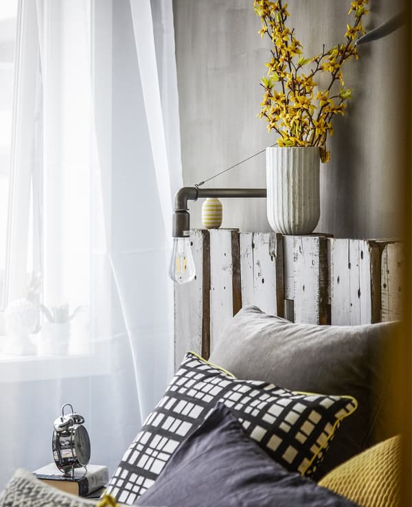 Cushions layered on a bed and voile curtains.