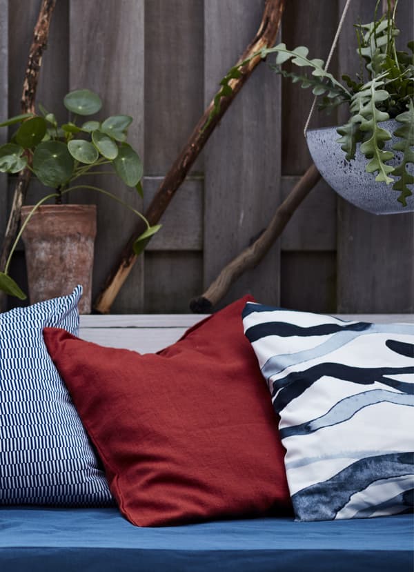 Cushions layered on a bench and hanging plants.
