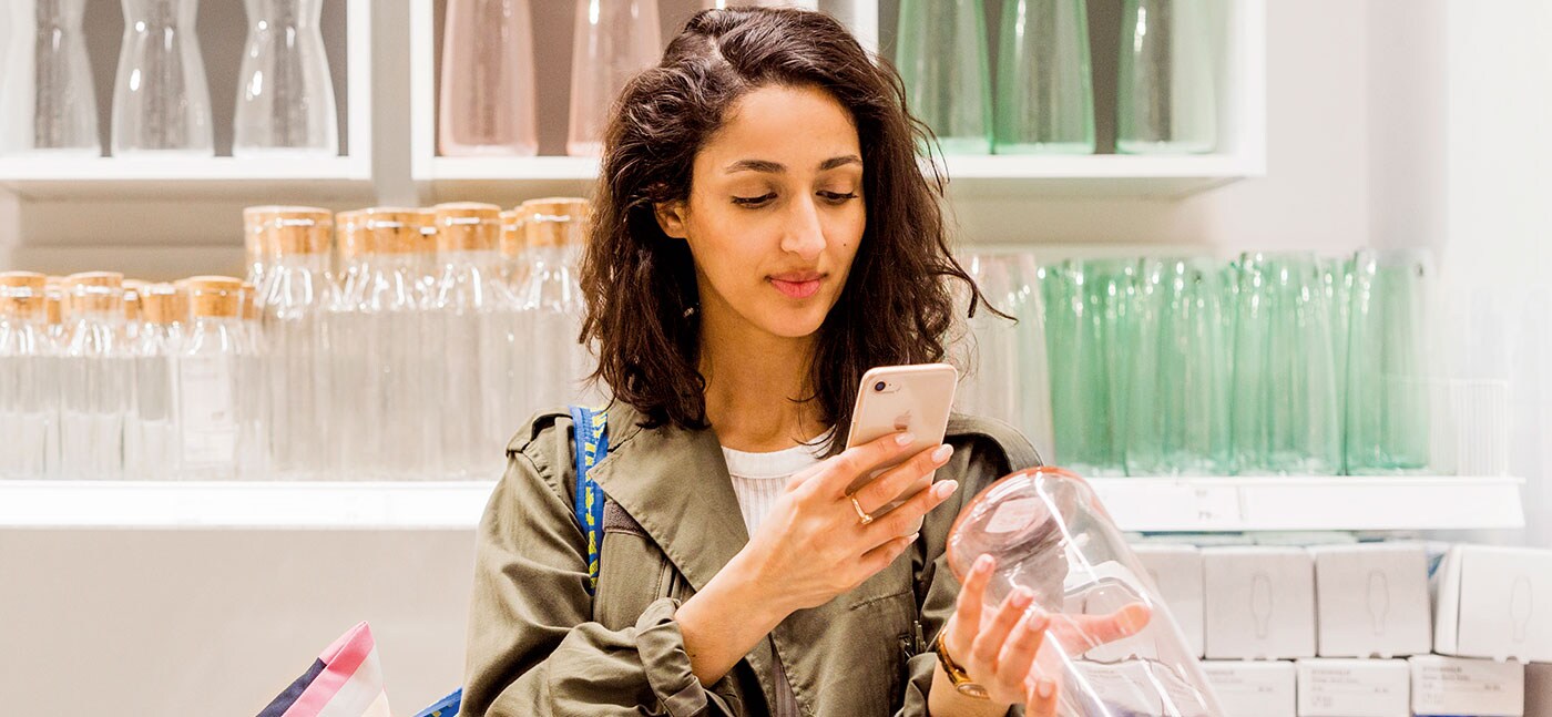 Customer checks her smartphone while choosing a glass bottle in the IKEA Market hall.