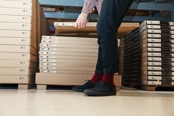 customer in black pants and checked shirt reaches for a flat packed item in an IKEA self-serve warehouse