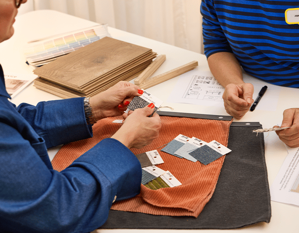 Customer speaking to IKEA co-worker dressed in blue regarding IKEA Home design service, holding up different colour swatches, as part of IKEA home design service