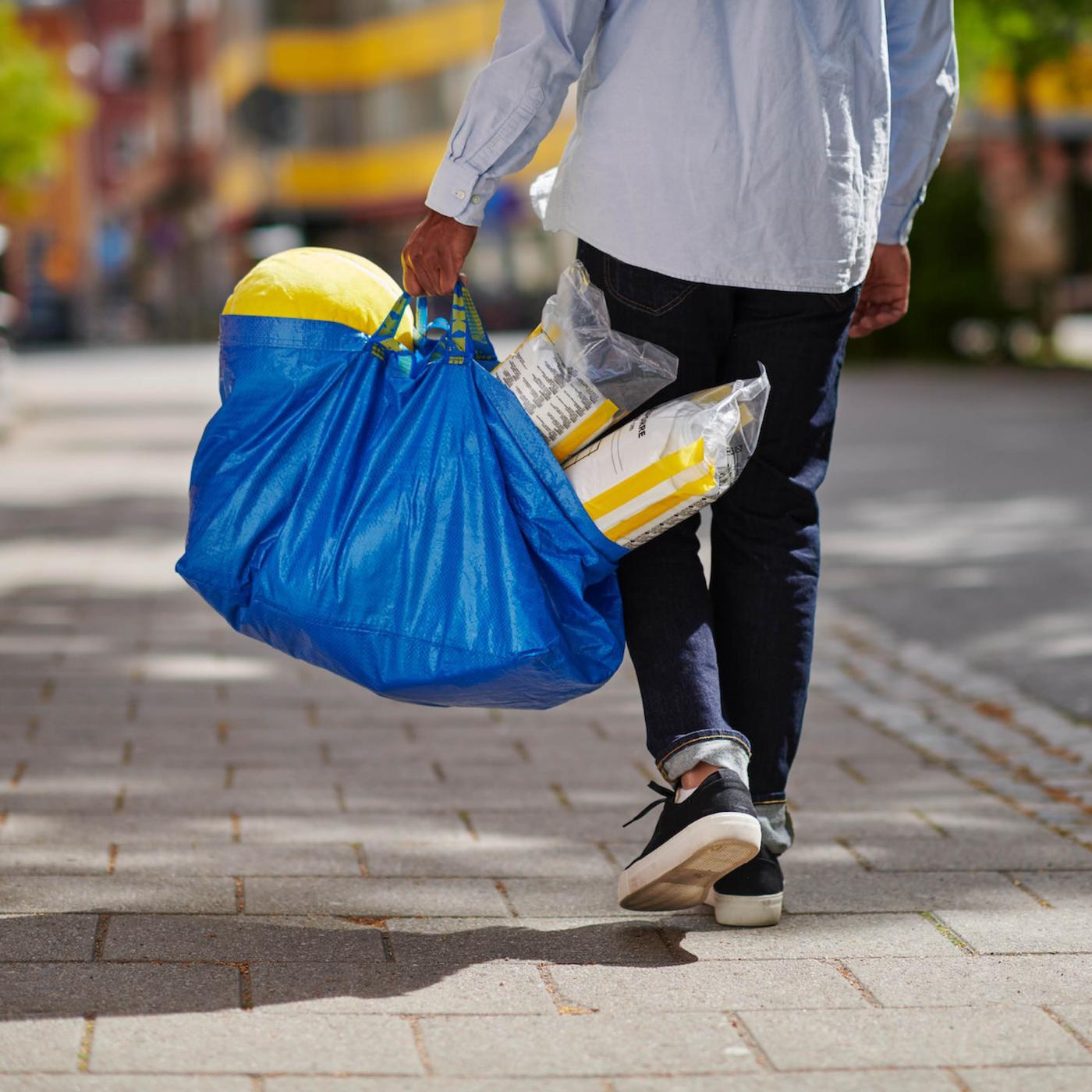 Customer walking around the streets with a blue IKEA bag full of products.