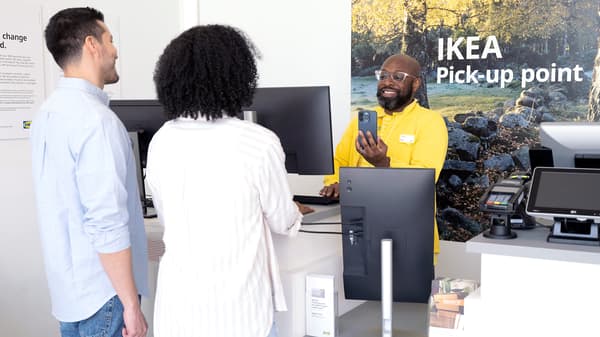 Customers at IKEA pickup counter receiving order from employee at service desk