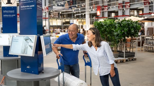 Customers pointing at display screens inside an ikea store