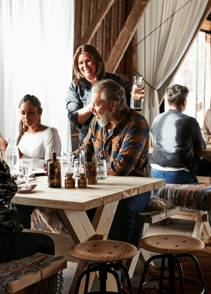 Customers sat at a restaurant table next to empty stools and smiling