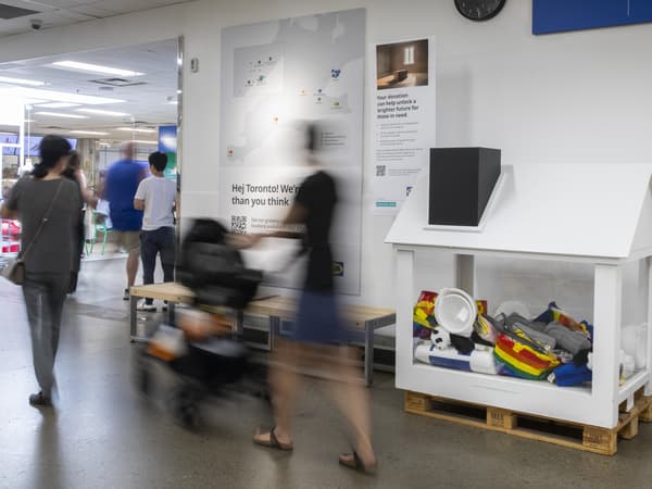 customers walk past house-shaped donation bin at IKEA store