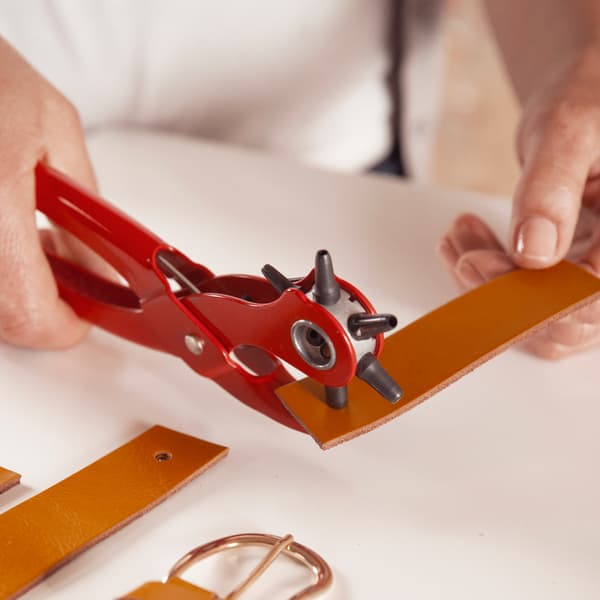Cut an old leather belt into 12 cm pieces and make two holes in it with pliers.