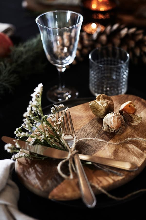 Cutlery, attached with a dried flower twig and a piece of hemp string placed decoratively on a wooden board.