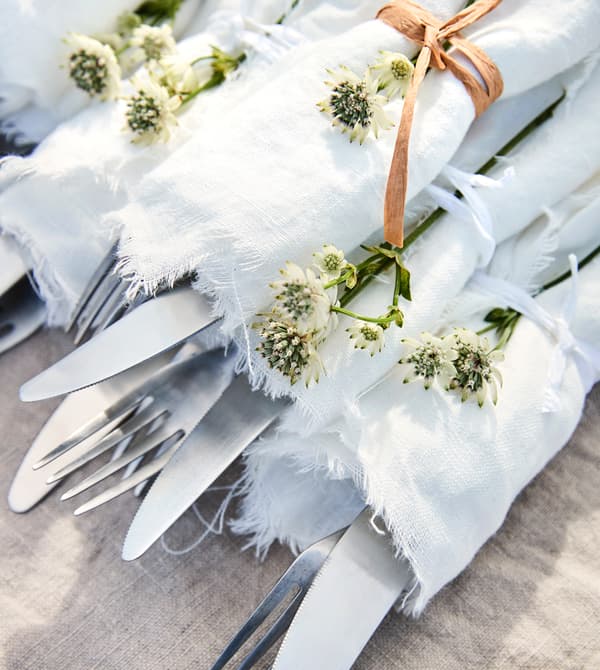 Cutlery is wrapped in white linen and bound with twine.