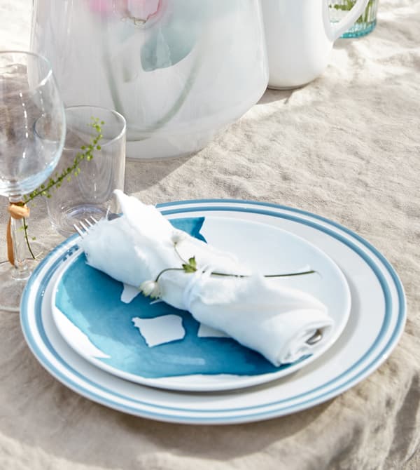 Cutlery wrapped in white linen and bound with a ribbon sits on a plate.