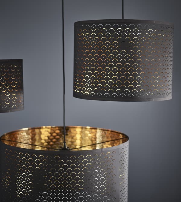 Cylindrical NYMÖ lamp shades with dark blue on the outside and a brass colour on the inside.
