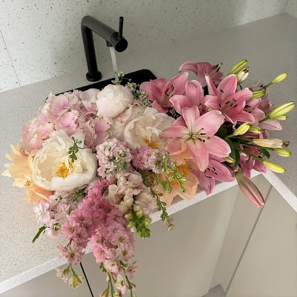 Czarny zlew kuchenny wypełniony kwiatami.