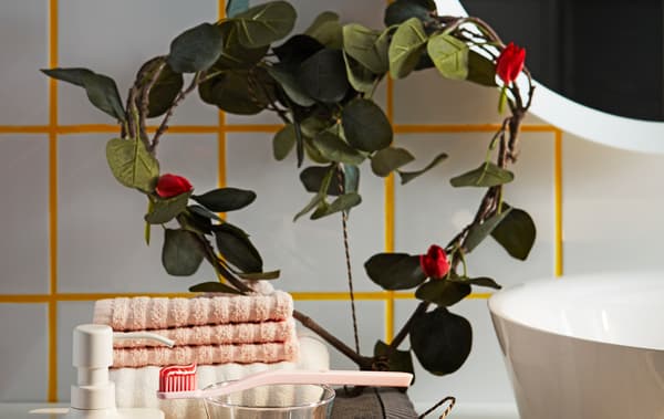 Dahan daun tiruan pokok kayu putih IKEA SMYCKA berwarna hijau yang berbentuk seperti hati, menghias para bilik mandi.