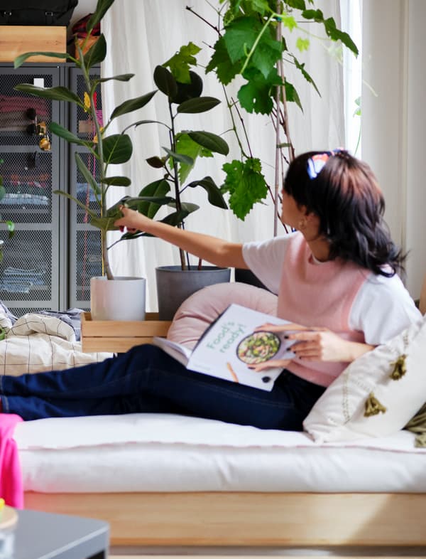 Dame die op de bank een kookboek aan het lezen is.