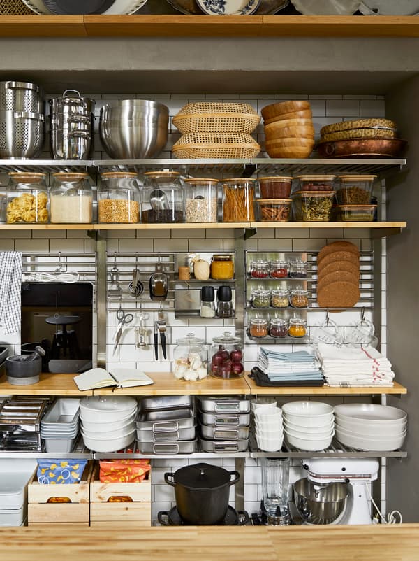 Dans le style armoire à provisions, mur de cuisine avec rangements ouverts construits à partir d’étagères KUNGSFORS, avec des pots remplis d’aliments secs et des ustensiles de cuisson.