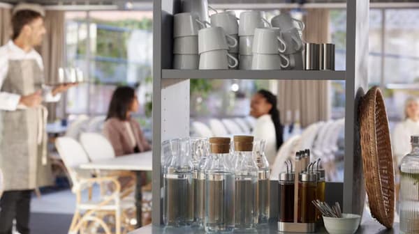 Dans un restaurant, un stand de rangement avec des carafes vides, des portes huiles et des tasses empilées