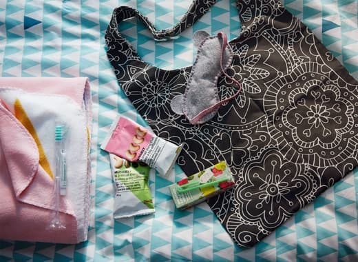 Dans un sac VÄNSKAPLIG noir, déposez quelques collations, boîtes à boire et un loup. Quel joli petit cadeau de bienvenue pour l'amie qui dort à la maison ! Le sac à motif floral est assez grand pour contenir une couverture.