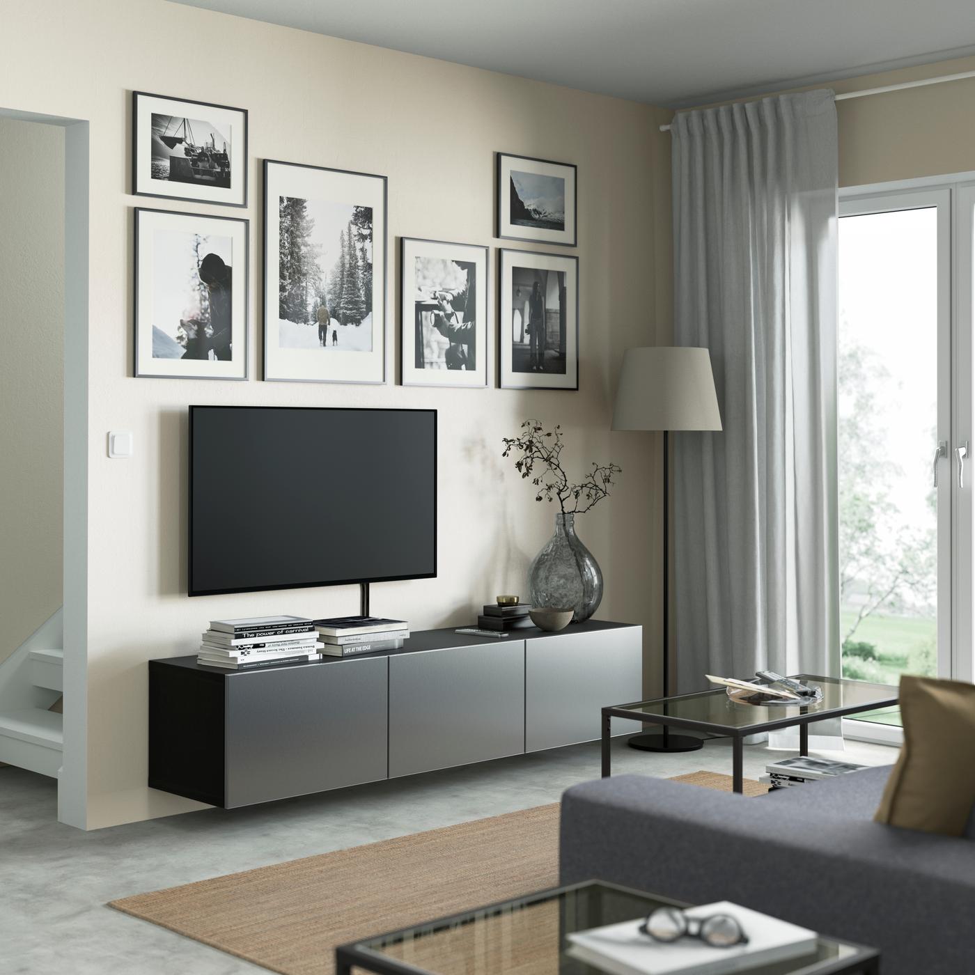 Dans un salon, un banc TV BESTA avec des portes RIKSVIKEN.