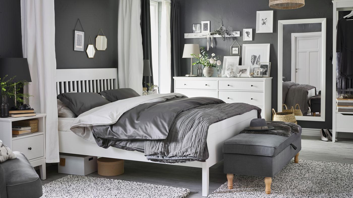 Dans une chambre à coucher, un lit IDANÄS blanc, une table de chevet et une commode, et du linge de lit LUKTJASMIN