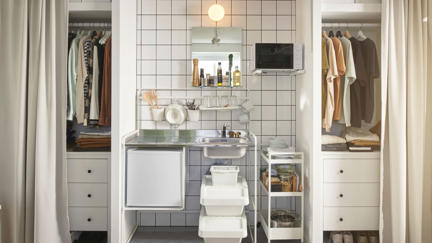 Dans une chambre d’étudiant en colocation, une minicuisine SUNNERSTA est installée entre deux armoires-penderies. Des rideaux sont suspendus devant les armoires-penderies.