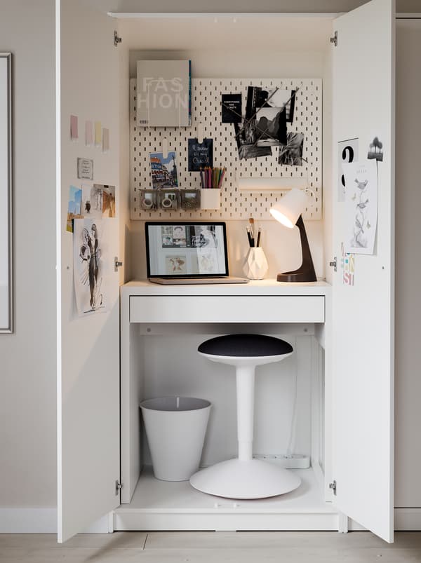 Dans une garde-robe KLEPPSTAD, un bureau MICKE, un tabouret dessinateur NILSERIK, une lampe et un panneau perforé forment un espace de travail compact.