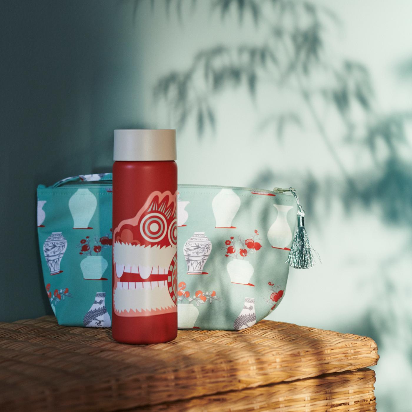Dappled light falling on A FÖSSTA insulated mug and FÖSSTA travel bag standing on top of a wicker chest.