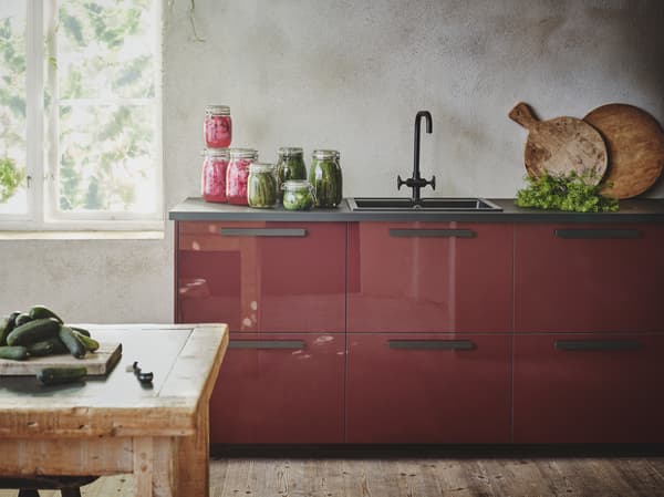 Dapur berwarna merah coklat gelap yang berkilat dengan permukaan atas kaunter, pemegang dan sink berwarna hitam terletak di ruang ala desa dengan dinding bertekstur berwarna kelabu.