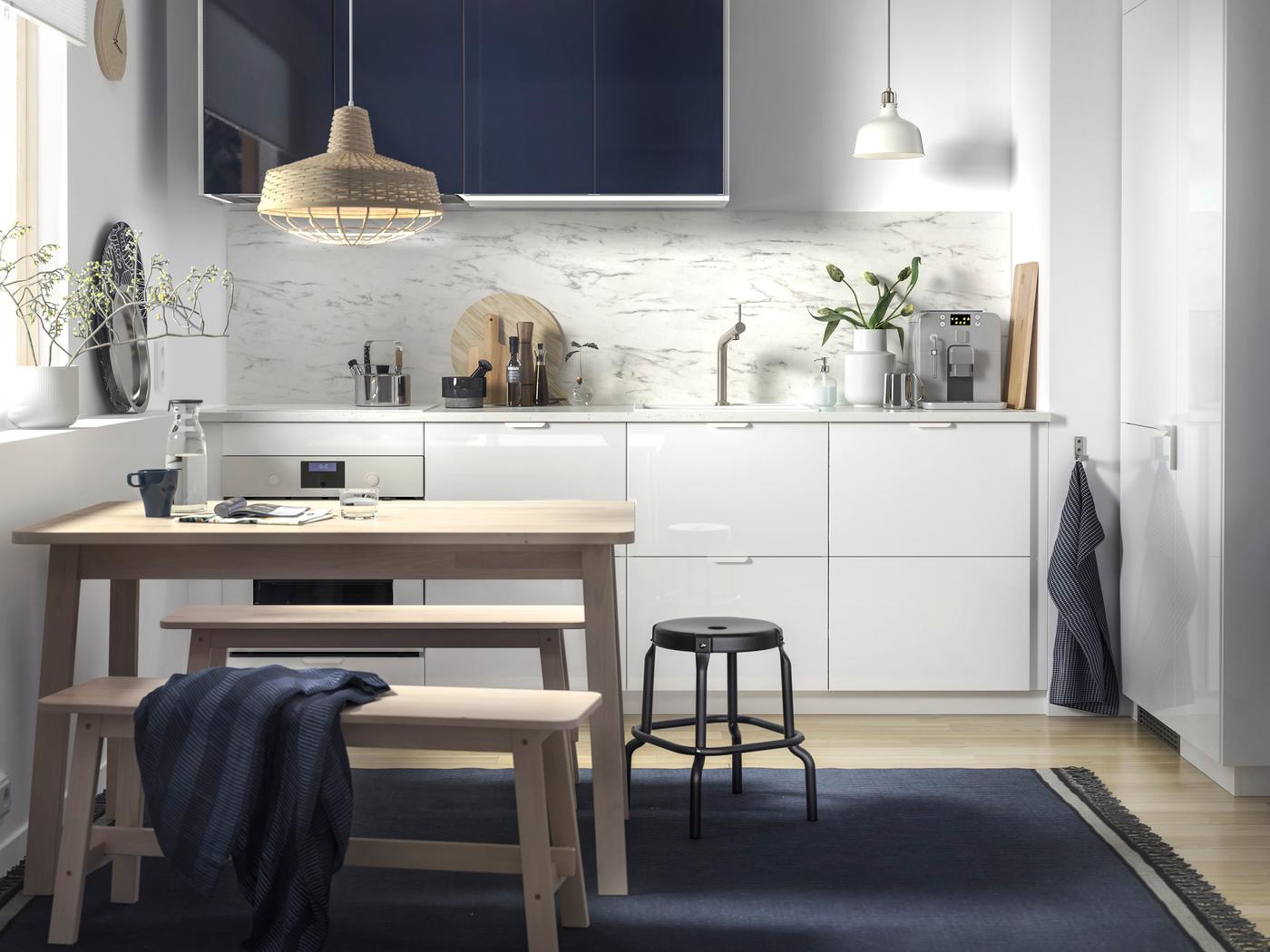 Dapur dengan meja NORRÅKER buatan kayu birch warna putih, bangku NORRÅKER buatan kayu birch warna putih, dan lampu pendan buatan buluh digantung di atasnya.