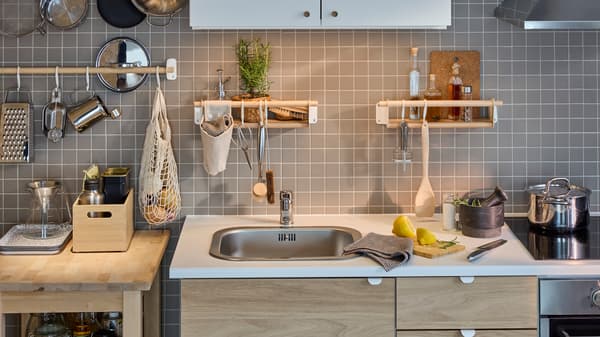 Dapur ENHET berwarna putih/kesan kayu oak di tepi dinding berjubin berwarna kelabu dengan rel kayu birch, dua para-para dinding kayu birch dan kabinet dinding berwarna putih.