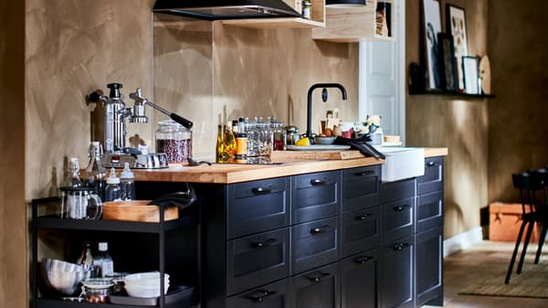 Dapur kecil yang dilengkapi serba indah dengan kabinet dinding terbuka yang kecil, kipas dapur dan bahagian hadapan laci LERHYTTAN berwarna gelap.
