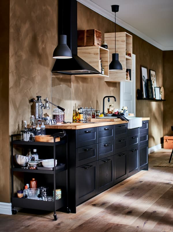 Dapur kecil yang dilengkapi serba indah dengan kabinet dinding terbuka yang kecil, kipas dapur dan bahagian hadapan laci LERHYTTAN berwarna gelap.