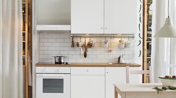 Dapur KNOXHULT berwarna putih dengan periuk keluli tahan karat terletak pada hob, periuk, kuali dan perkakas dapur tergantung pada rel.
