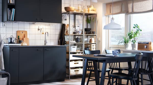 Dapur monokrom yang anggun dengan kabinet berwarna antrasit, meja dan kerusi berwarna hitam serta rak logam terbuka.