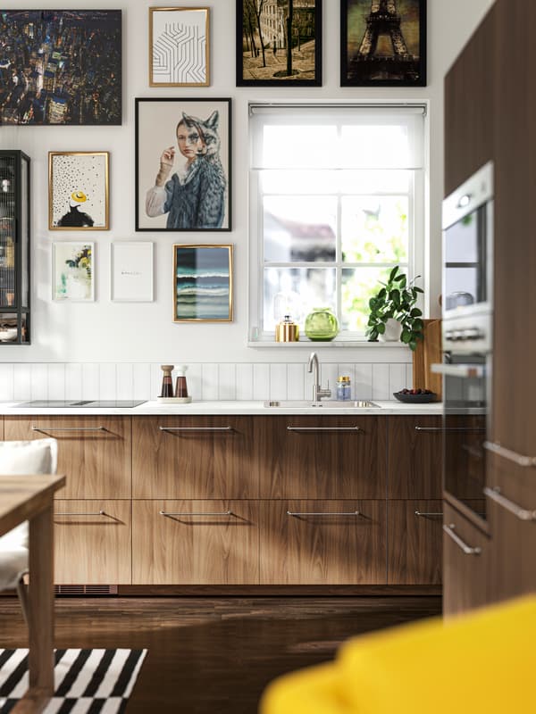 Dark brown kitchen with white walls and lots of frames on these walls