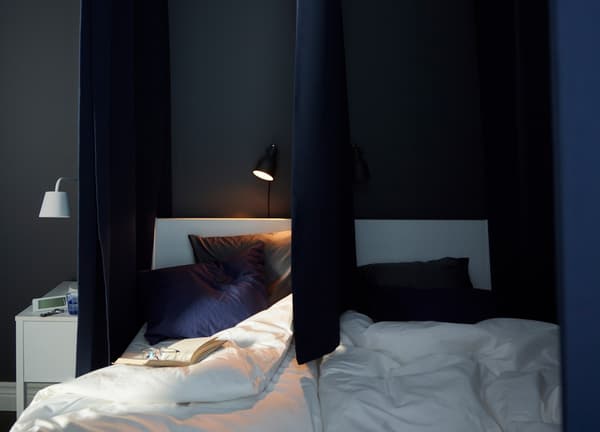 Dark curtains hang at the sides and down the middle of this bed to make it possible to create separate sleeping zones.
