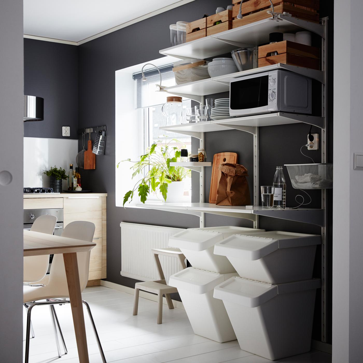 Dark grey kitchen with wall-mounted white shelves with waste sorting units underneath.