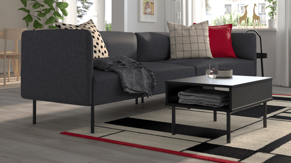 Dark grey LILLEHEM 3-seater sofa in a modern living space, styled with red and black cushions, black coffee table, and geometric rug