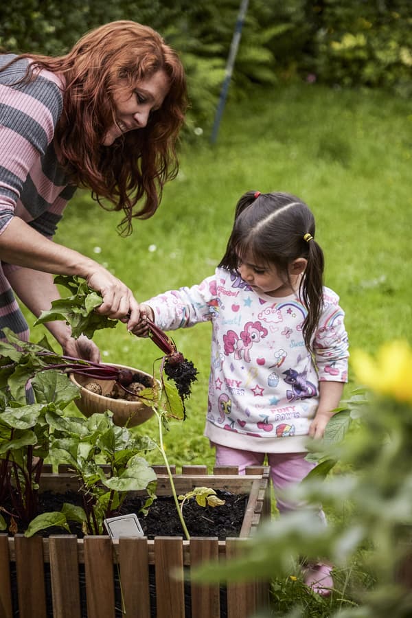 Dark-haired child helping mother in the garden.