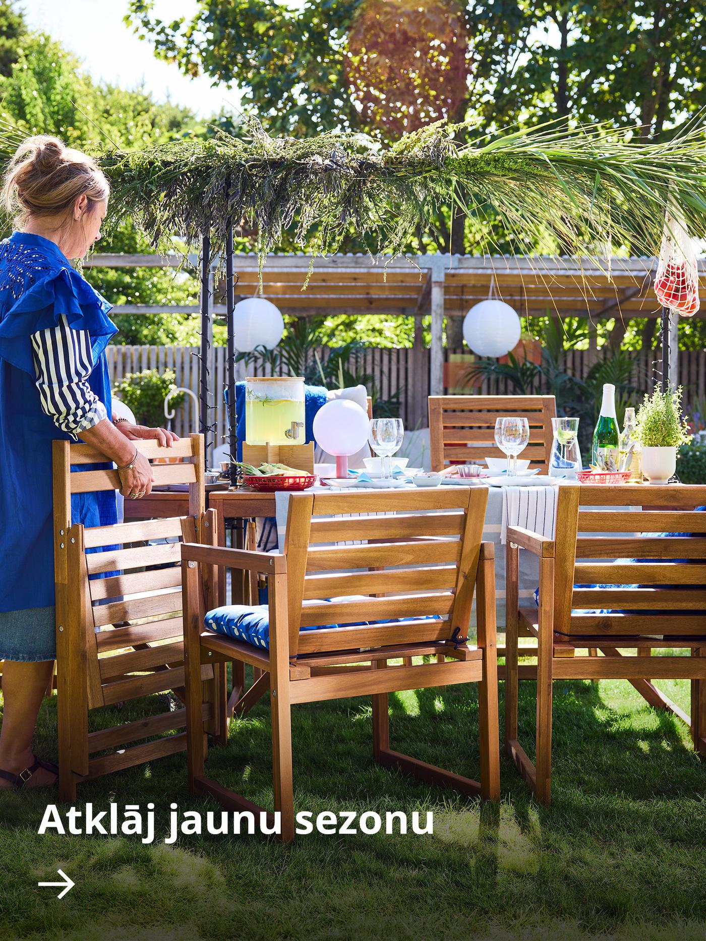 Dārza lapene ar melnu GRILLSKÄR ogļu grilu un koka NÄMMARÖ āra virtuves mēbelēm.
