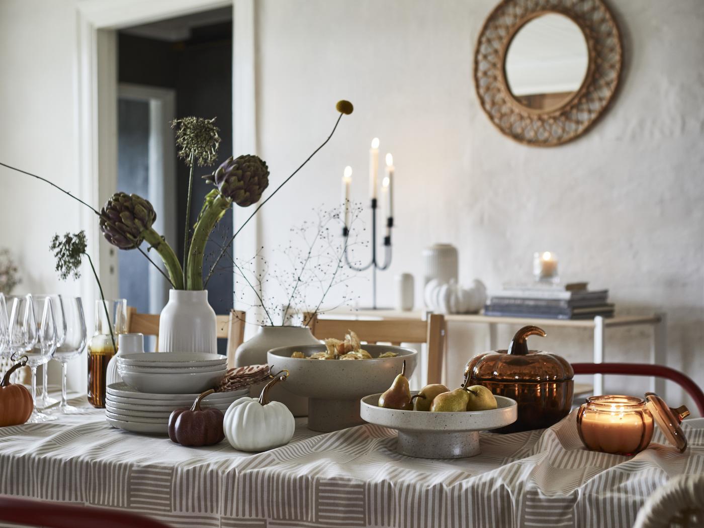 Das Bild zeigt die neuen Produkte der limitierten IKEA HÖSTAGILLE Kollektion auf einer gedeckten Tafel: Kerzen, Geschirr, Dekoobjekte 