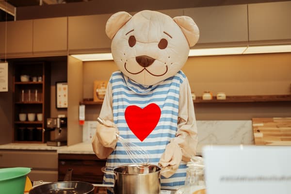 Das Bild zeigt ein Fabler Björn Maskottchen beim Kochen.