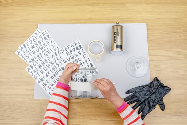 Das Glas wird mit Buchstaben beklebt.