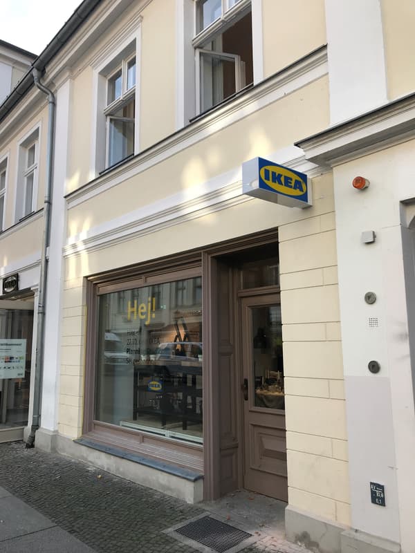 Das IKEA Planungsstudio von außen, es ist eine beige Gebäudefront, ein IKEA Logo und der Schriftzug Hej! zu sehen.