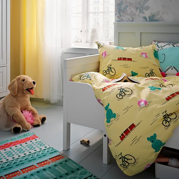 Das KÄPPHÄST Bettwäscheset mit Spielzeugen bedruckt auf einem Kinderbett. Auf dem Boden daneben ist ein Stofftier in Hundeform zu sehen.