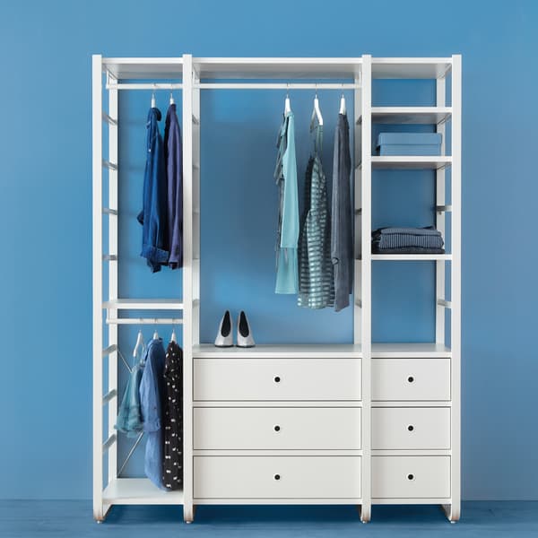 Davanti a una parete blu, una combinazione di guardaroba ELVARLI bianca con vestiti blu appesi ai bastoni appendiabiti.