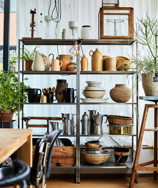 De la poterie et des ustensiles de cuisine exposés sur de grande étagères en métal.
