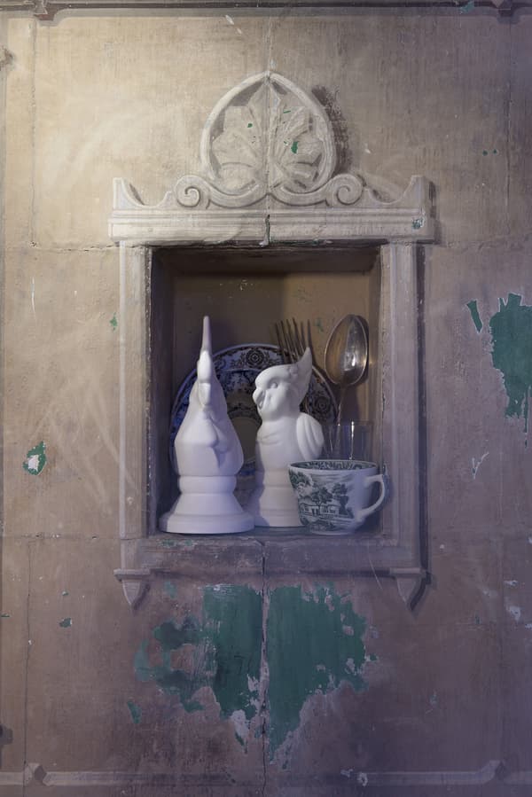 De la vaisselle et deux oiseaux blancs décoratifs nichés dans le mur.