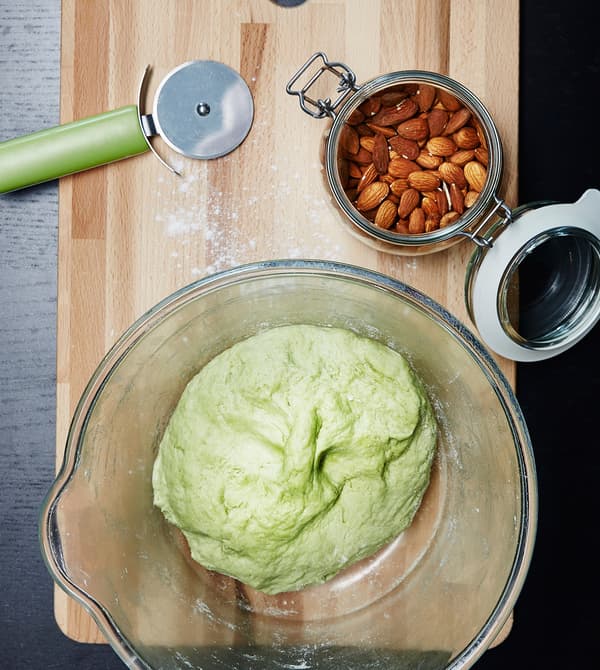 Decoració de Halloween amb un bol de vidre amb una massa verda damunt una taula de tallar de fusta.