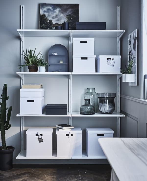 Decoración de escritorio con estantes de almacenaje abierto con cajas, jarrones y una planta.